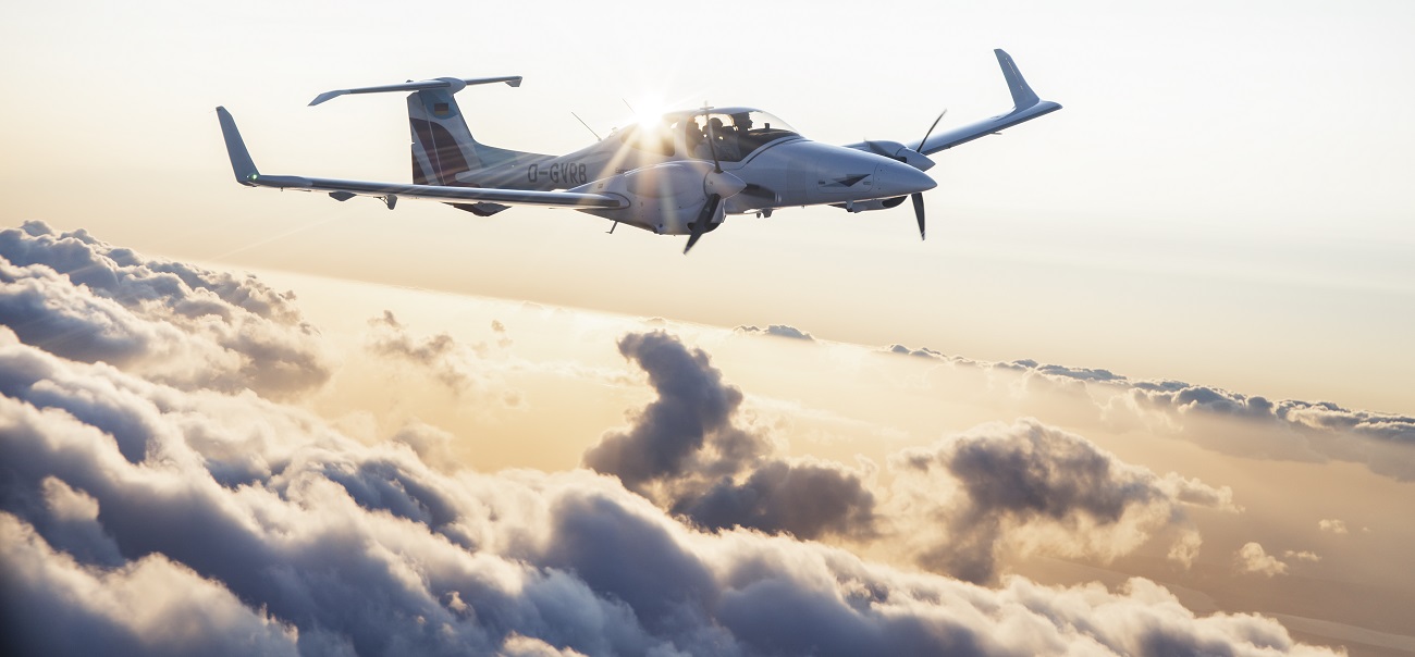 A DA42 from the European Flight Academy flies above the clouds at sunset.