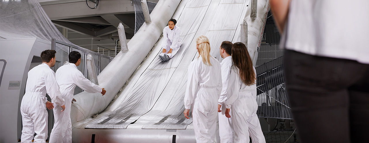 Participants of a Safety and Emergency Training practice the use of a rescue slide on a simulator