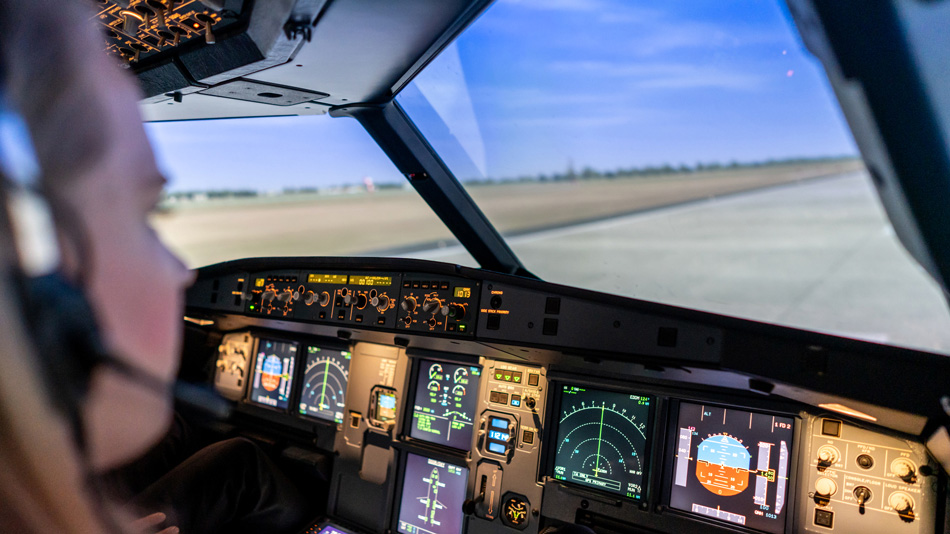 A pilot sits in a cockpit simulator and looks at a runway