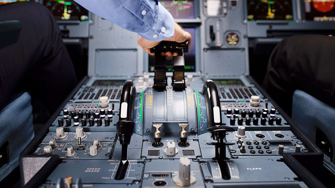 A pilot operates the thrust levers in an aircraft cockpit