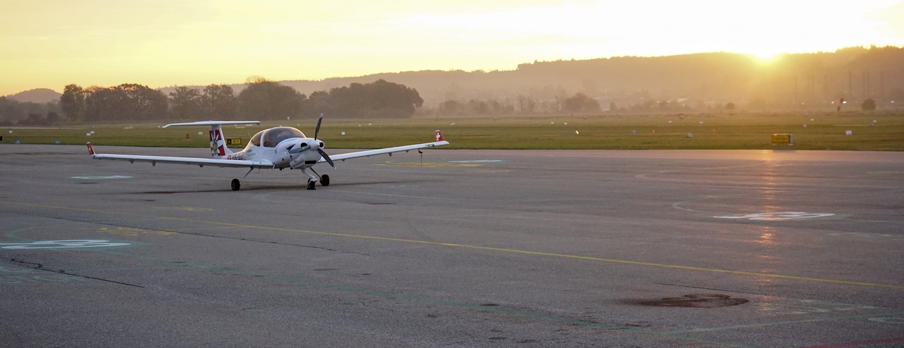 A training aircraft for ab initio pilot training is on a runway at sunrise.