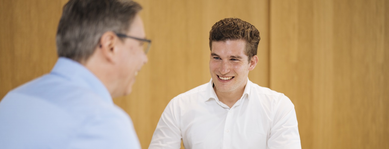 Two people in a job interview are sitting across from each other and laughing.