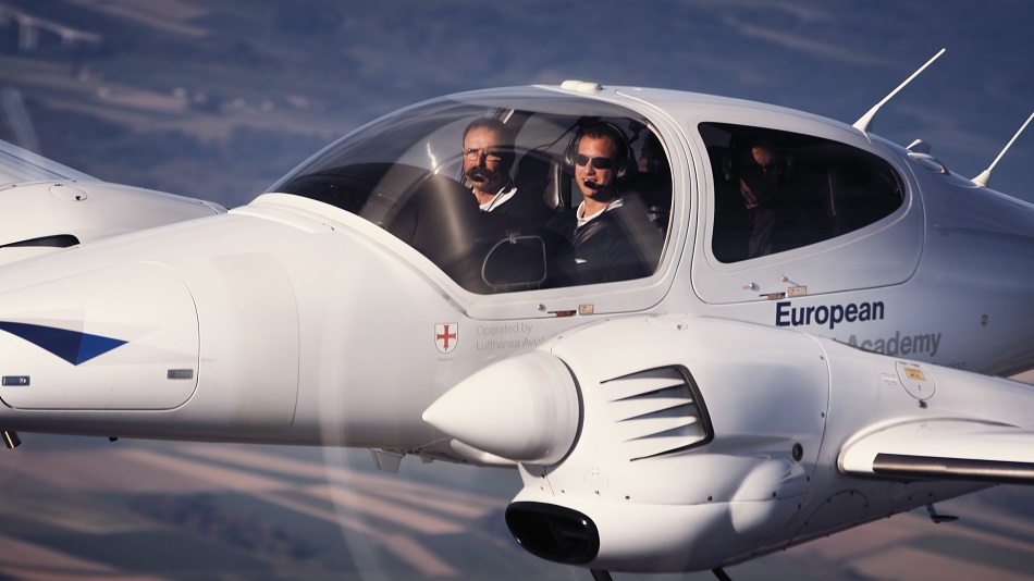  Two people sit in the cockpit of a training aircraft and fly.