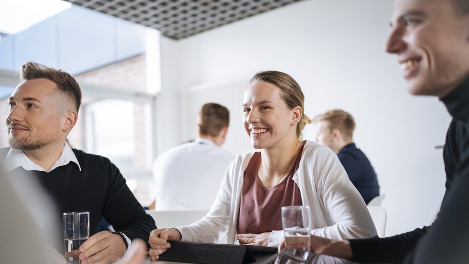  Several people sit at a table and write. Keyrings, calculators and notebooks are on the table.