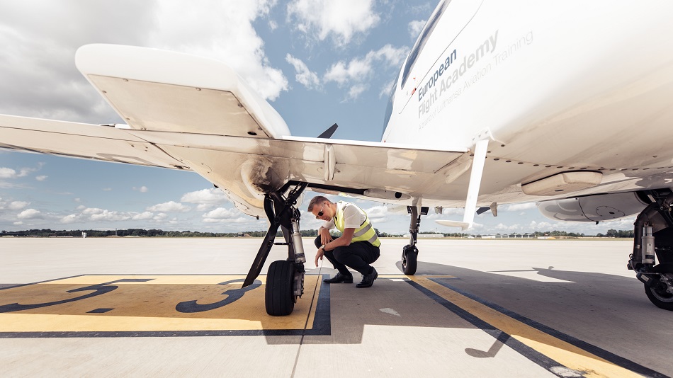 Eine Flugschüler:in der Flugschule der Lufthansa Group wirft einen prüfenden Blick auf den Reifen eines Schulungsflugzeuges.