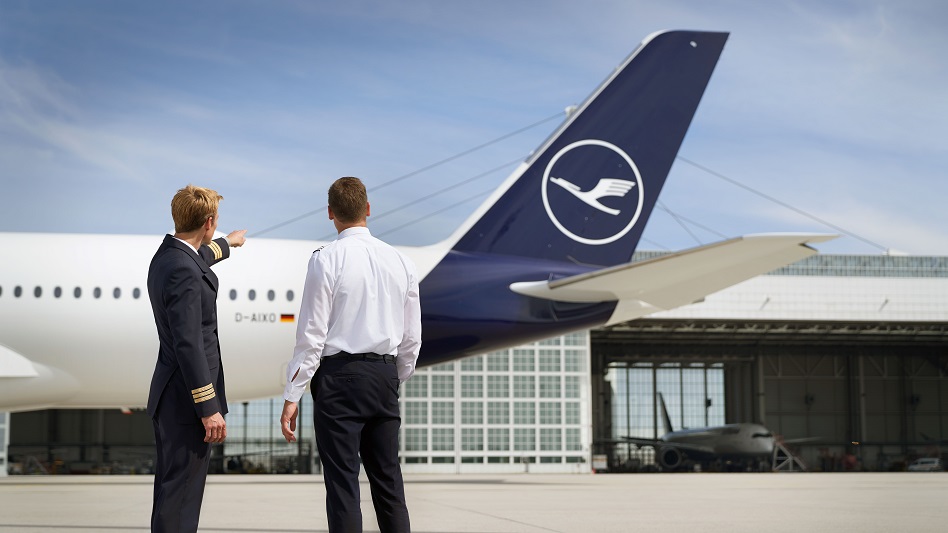 A first officer stands with a student pilot in front of an A350 and explains details.