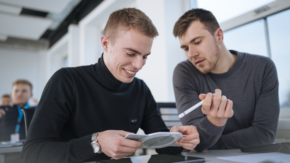 Eine Person sitzt an einem Tisch und tippt auf einem Taschenrechner.