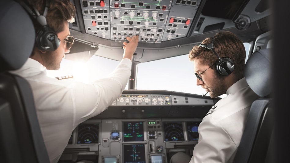 A captain and a second officer sit in a cockpit.