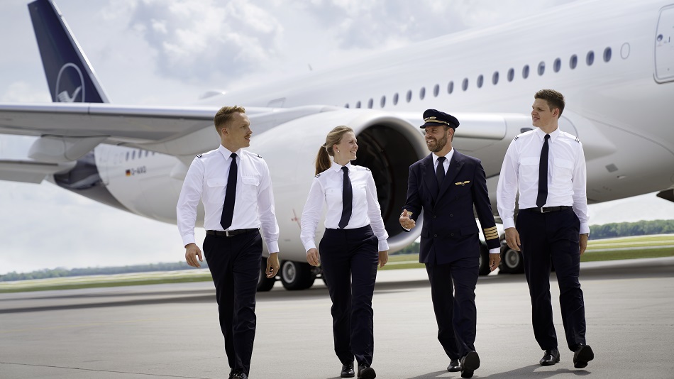A captain with three student pilots walk in front of an Airbus A350.