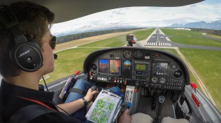 Eine Person sitzt in einem Schulungsflugzeug und steuert Richtung Landebahn.