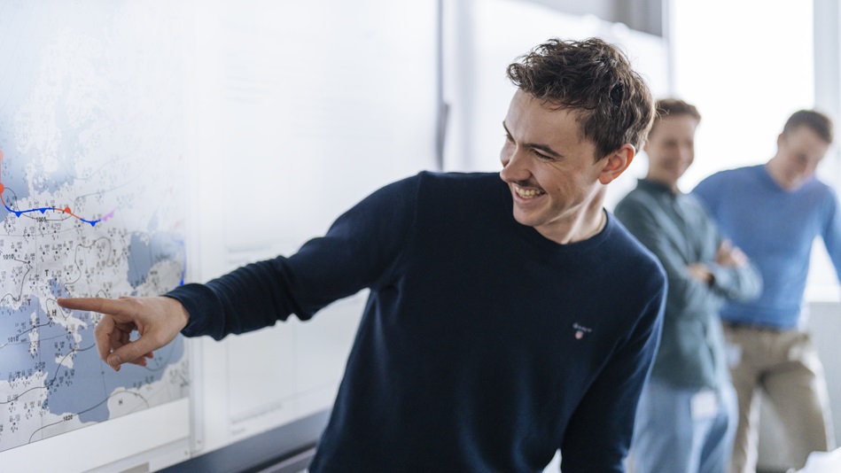 Mehrere Flugschüler:innen sitzen an einem Tisch, im Vordergrund arbeitet eine Flugschüler:in an einem Tablet.