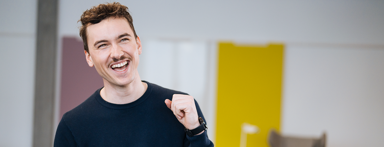 Im Vordergrund sieht man eine Person, die sich freut. Im Hintergrund sind 4 weitere Personen die ihren Erfolg feiern.